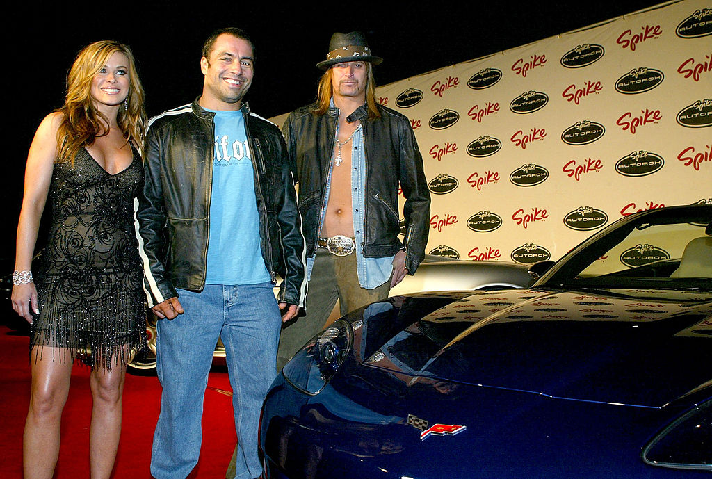 Carmen Electra, Joe Rogan, and Kid Rock standing next to a sports car