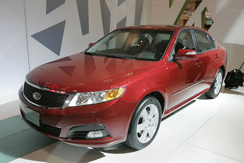 A red Kia Optima on display at an auto show