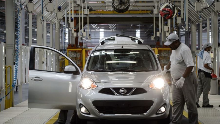Workers assemble a Nissan Versa in a factory