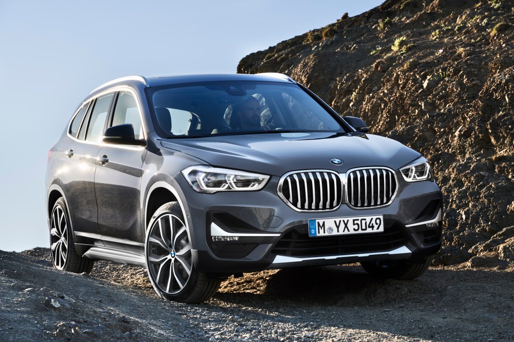 A charcoal grey 2020 BMW X1 driving down the countryside.