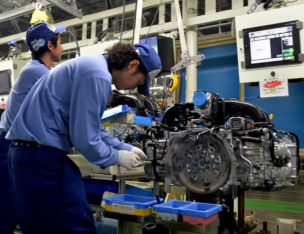 Workers assemble a Subaru engine on an assembly line