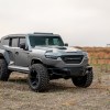 Gray Rezvani Tank SUV in a rocky desert field
