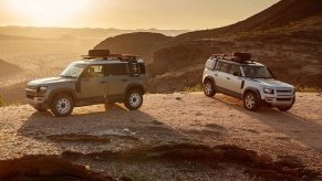 two land rover defenders in a remote desert scene with the sun giving backlighting