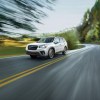 a white subaru forester crossover SUV at speed on a scenic road