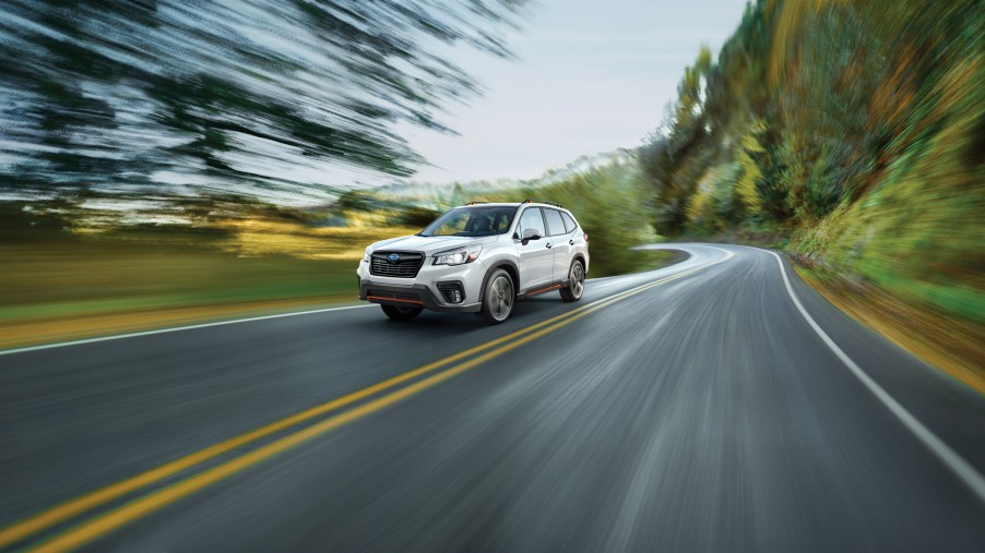 a white subaru forester crossover SUV at speed on a scenic road