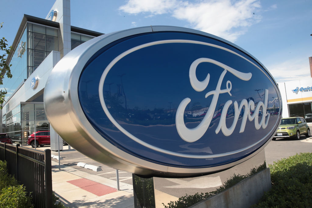 A sign sits in front of a Ford dealership