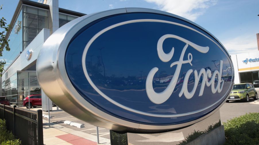 A sign sits in front of a Ford dealership
