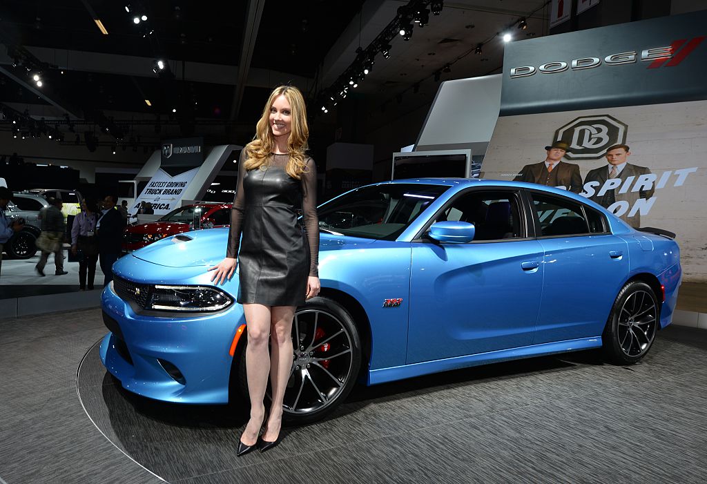 A model posing with a Dodge Charger at an auto show