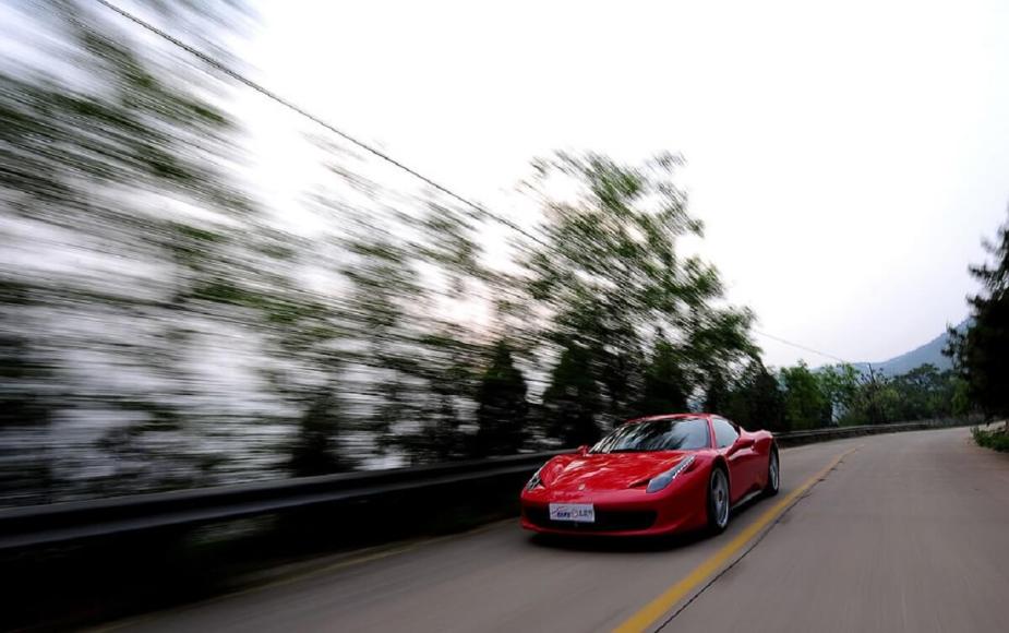 A red Ferrari 458 Italia, like the famed 2.7 GPA car, speeds down a back road.