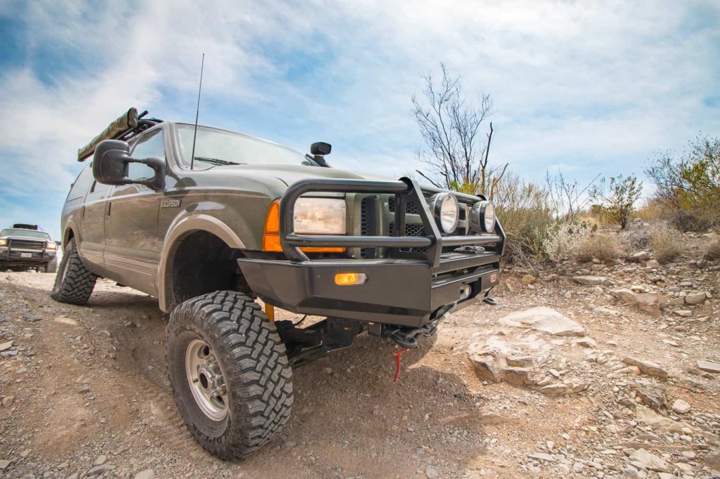 A lifted Ford Excursion on a dirt road during an overlanding trip
