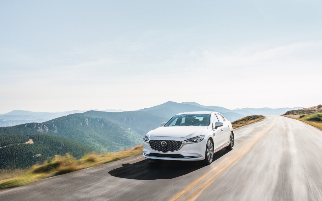 white mazda6 at speed on a scenic road against a mountainous backdrop