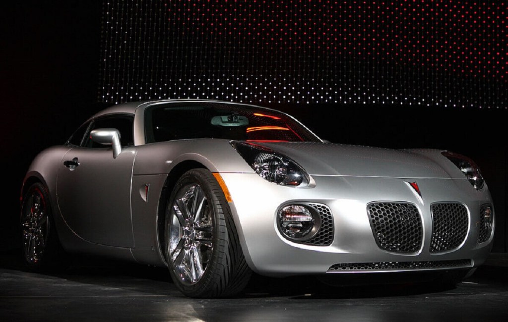A silver Pontiac Solstice parks on a stage.