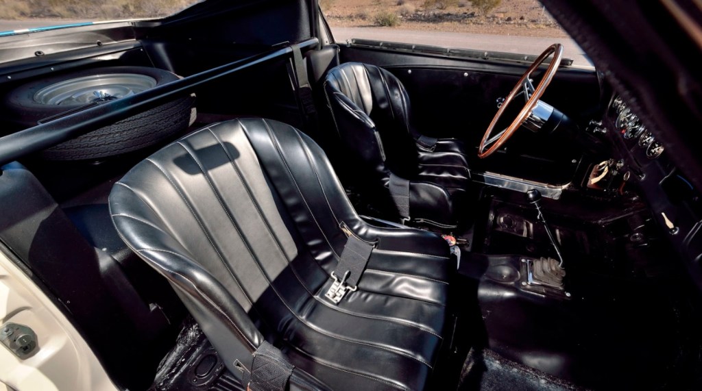 Black interior of 1965 Ford Shelby GT350R Mustang prototype, with fire extinguisher, bracing, and spare tire