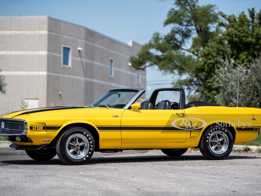 A yellow Shelby GT500 sits in the sun with its top down
