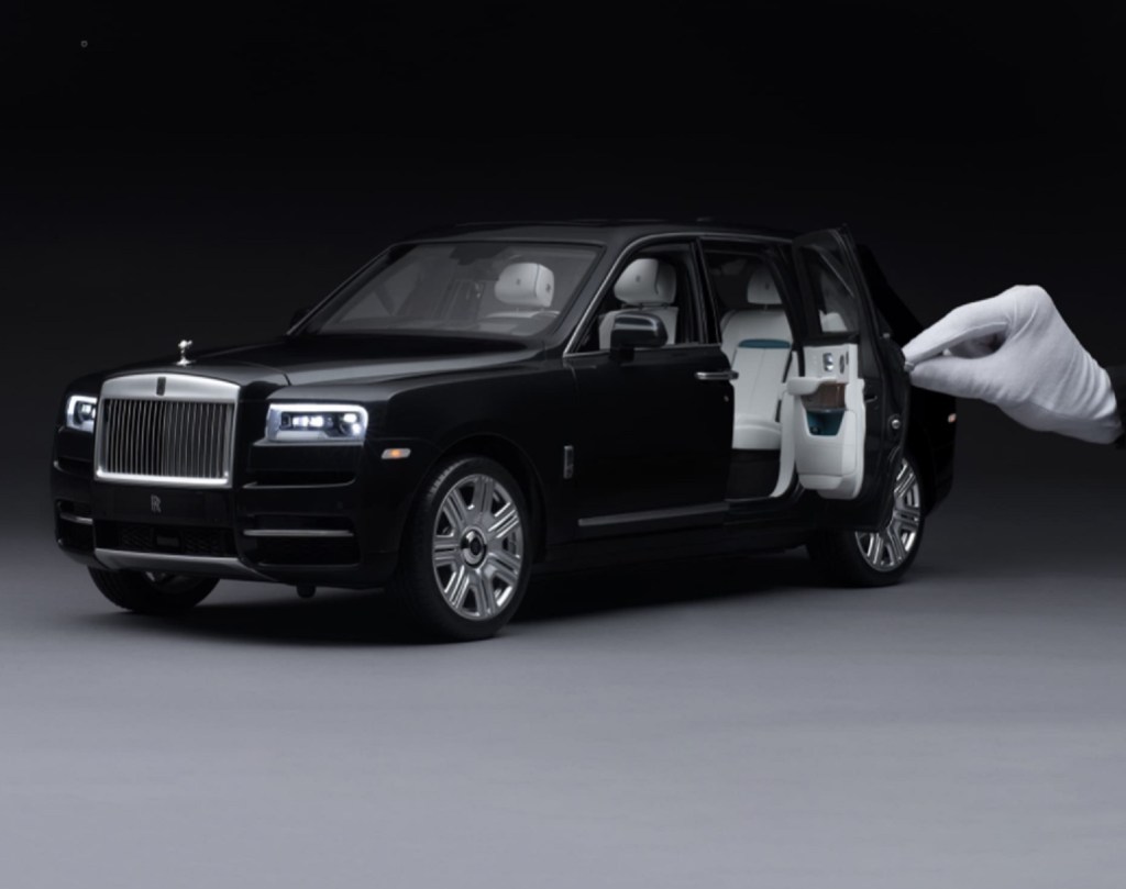 Black 1:8-scale Rolls-Royce Cullinan model with white-gloved hand for scale
