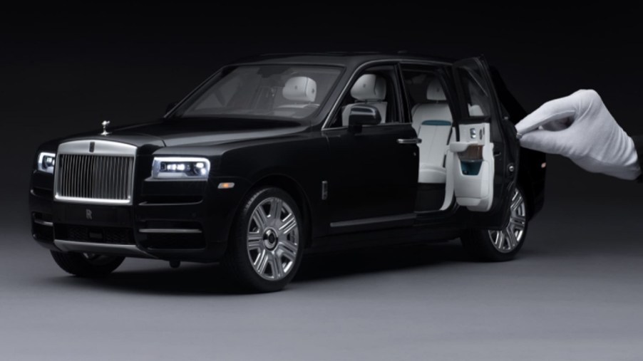 Black 1:8-scale Rolls-Royce Cullinan model with white-gloved hand for scale