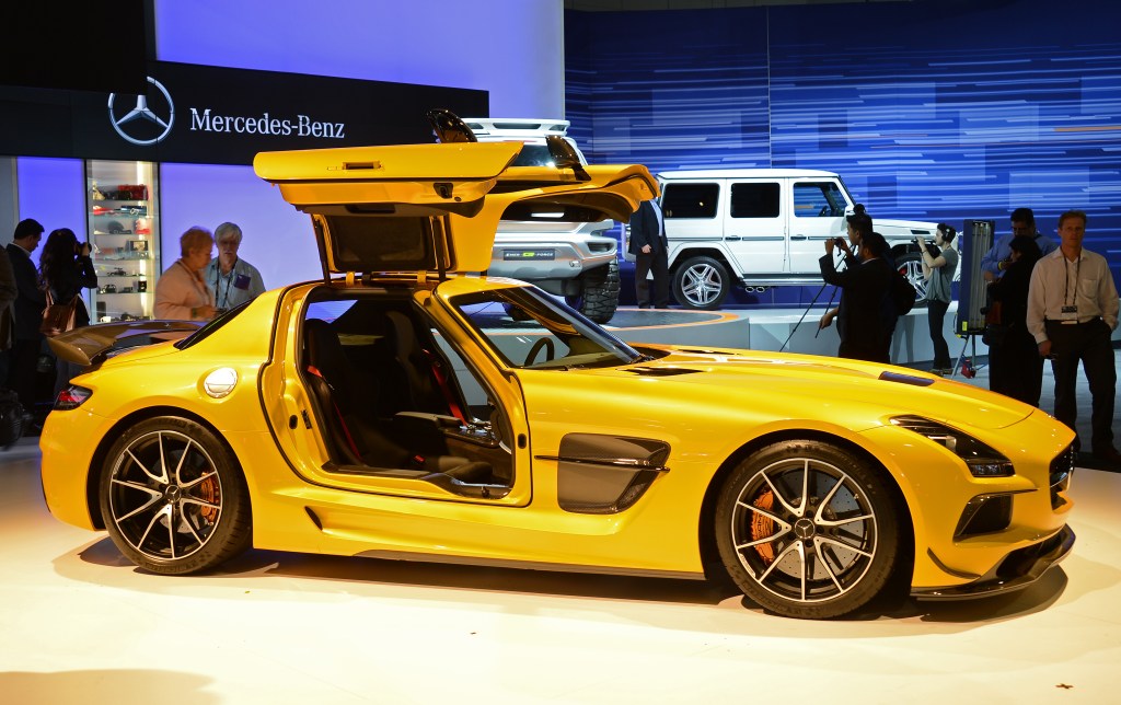 A yellow gullwing sports car from Mercedes sits on display at a car show
