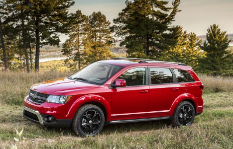 a red Dodge Journey parked in the grass