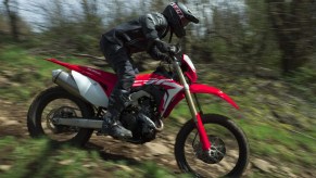 Red-and-white 2019 Honda CRF450X being ridden quickly down a forest trail