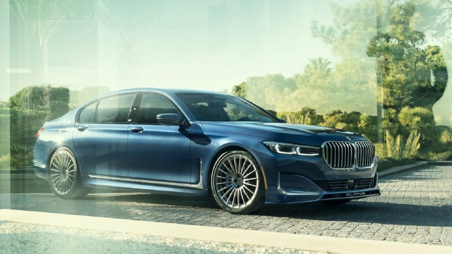 Dark blue 2020 Alpina B7 behind glass, with trees reflecting on the glass