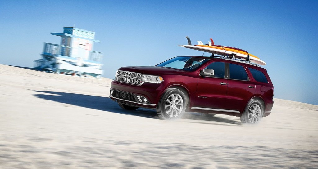 A red Dodge Durango toting surf boards on the beach
