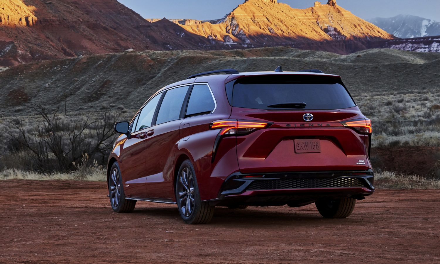 a deep red all-new Toyota Sienna, rear view in a desert landscape