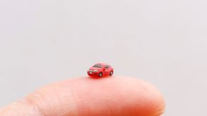 Red clay Honda car on the tip of a finger