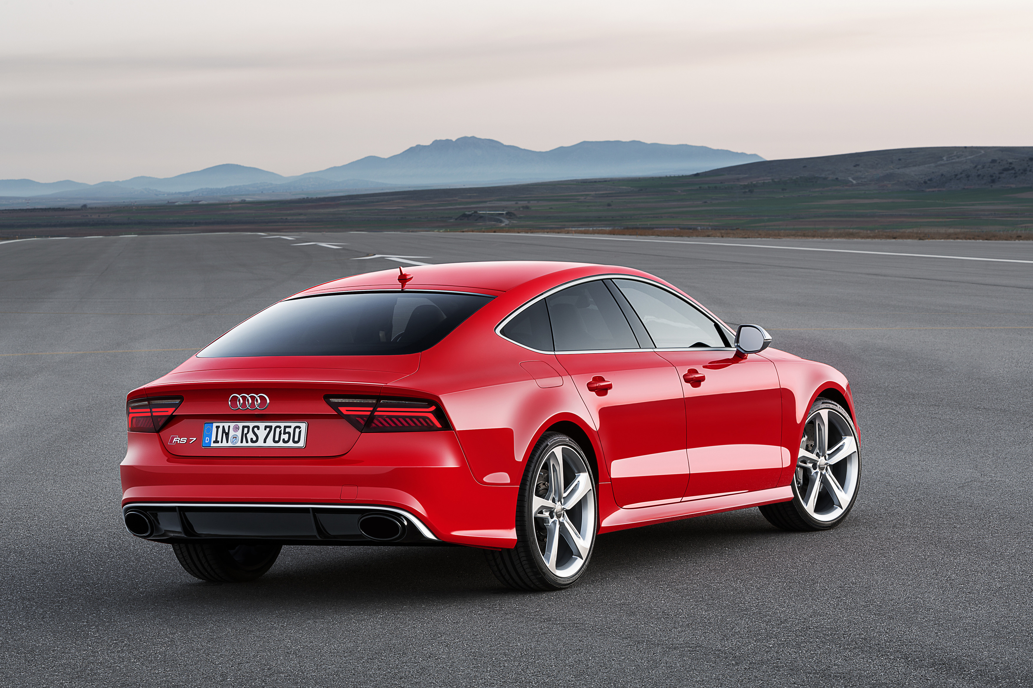 An Audi RS7 Sportback in Misano Red parked in the middle of a road with a mountain backdrop