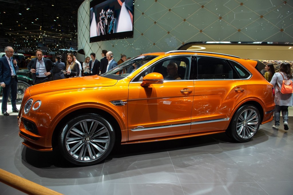 An orange Bentley Bentayga shines under the lights at a car show