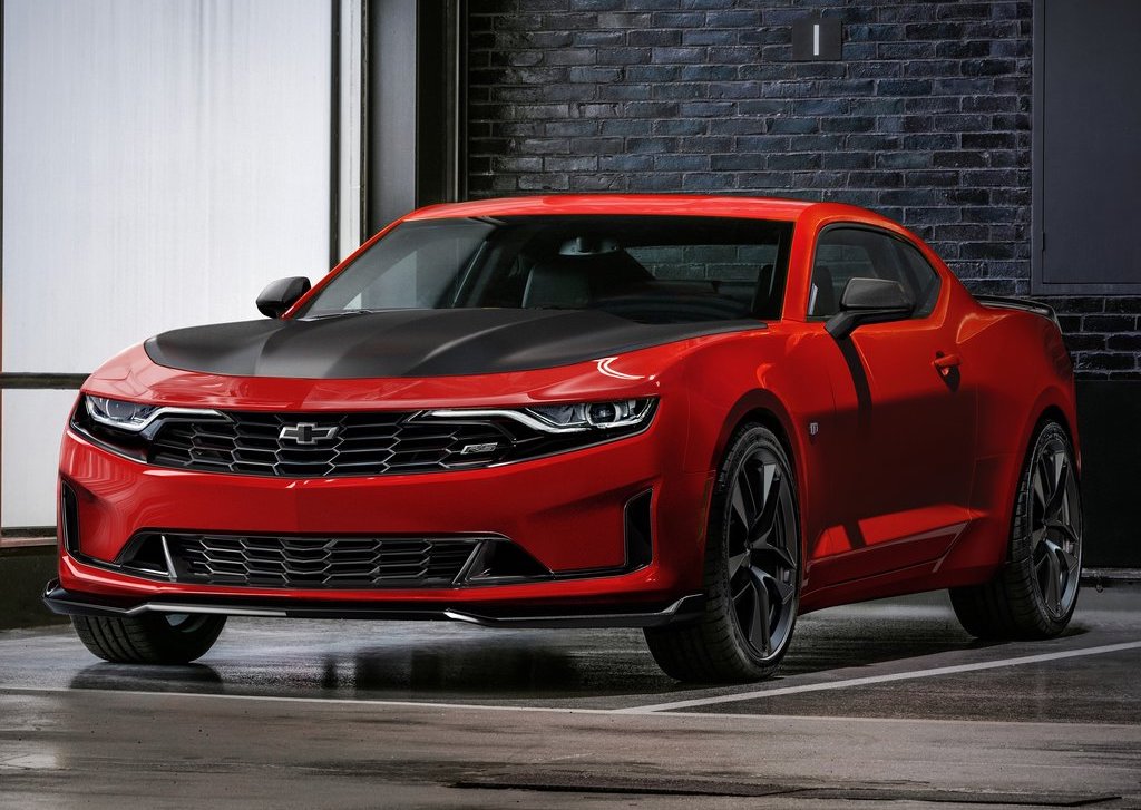 A red Camaro with a black hood parked on pristine concrete flooring. 