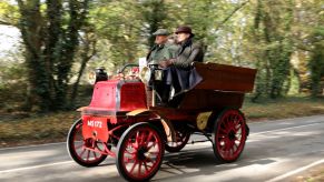 Two men riding an old car