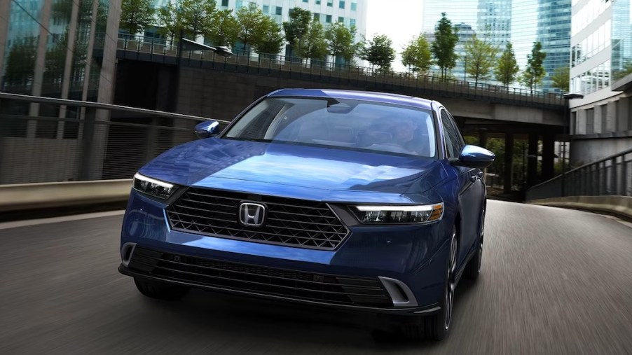 A blue Honda Accord midsize sedan is driving on the road.