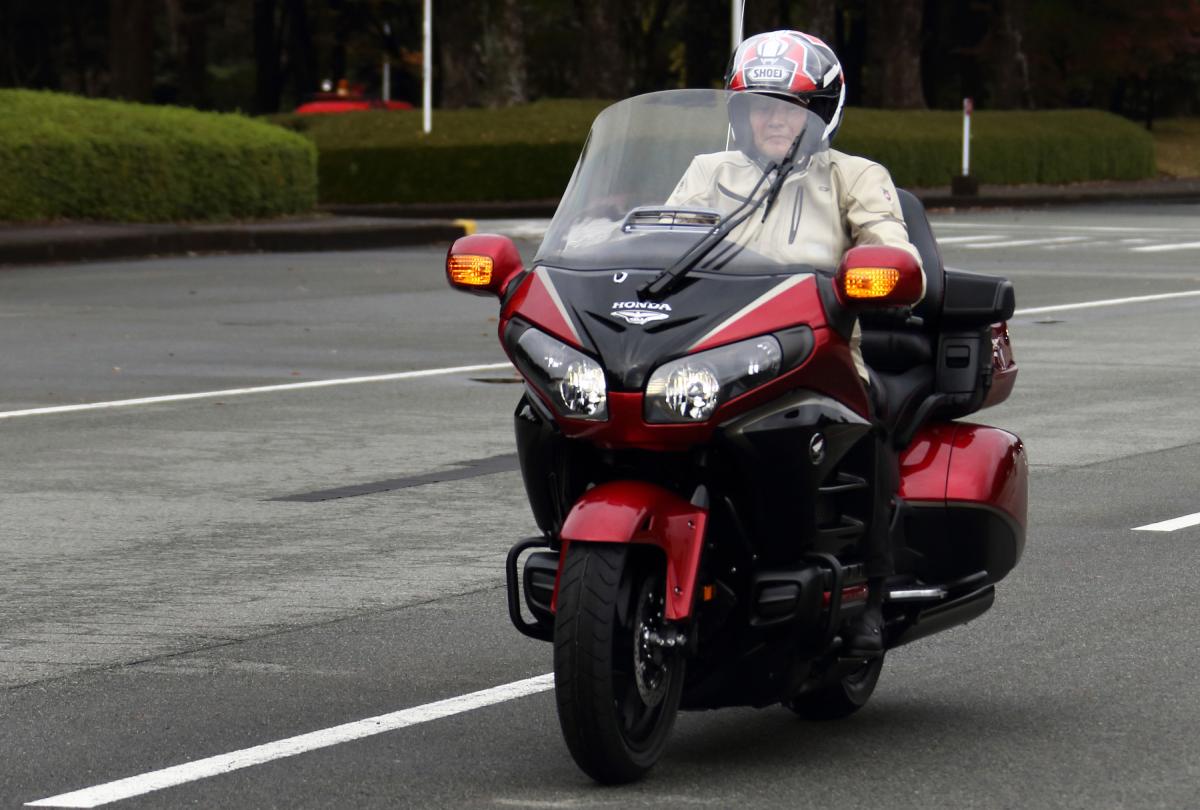 A person riding a Honda Gold Wing motorcycle down the road.