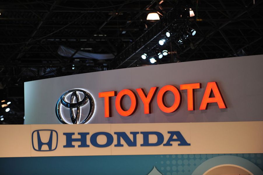 Toyota and Honda logos on display at an auto show