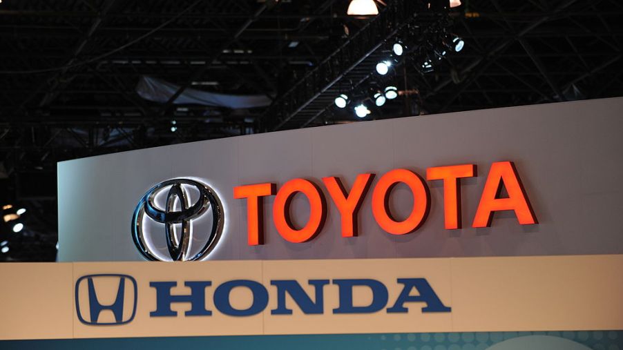 Toyota and Honda logos on display at an auto show