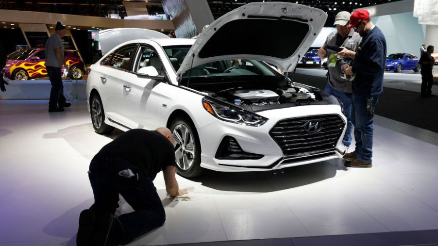 Workers prep around a Hyundai Sonata at the Hyundai 1272exhibit is shown at the 2018 North American International Auto Show
