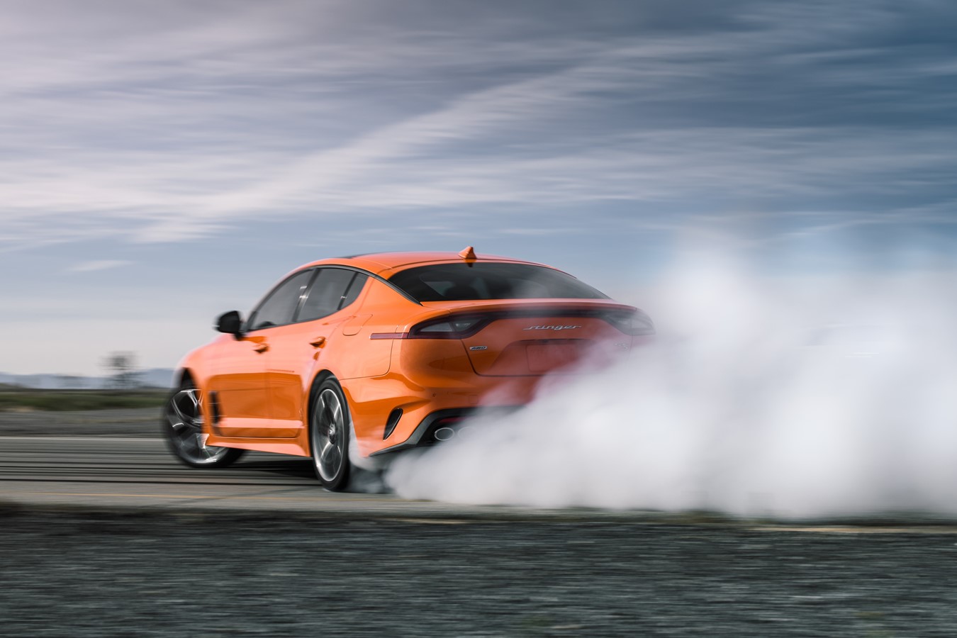 An orange Kia Stinger GTS performs a burnout