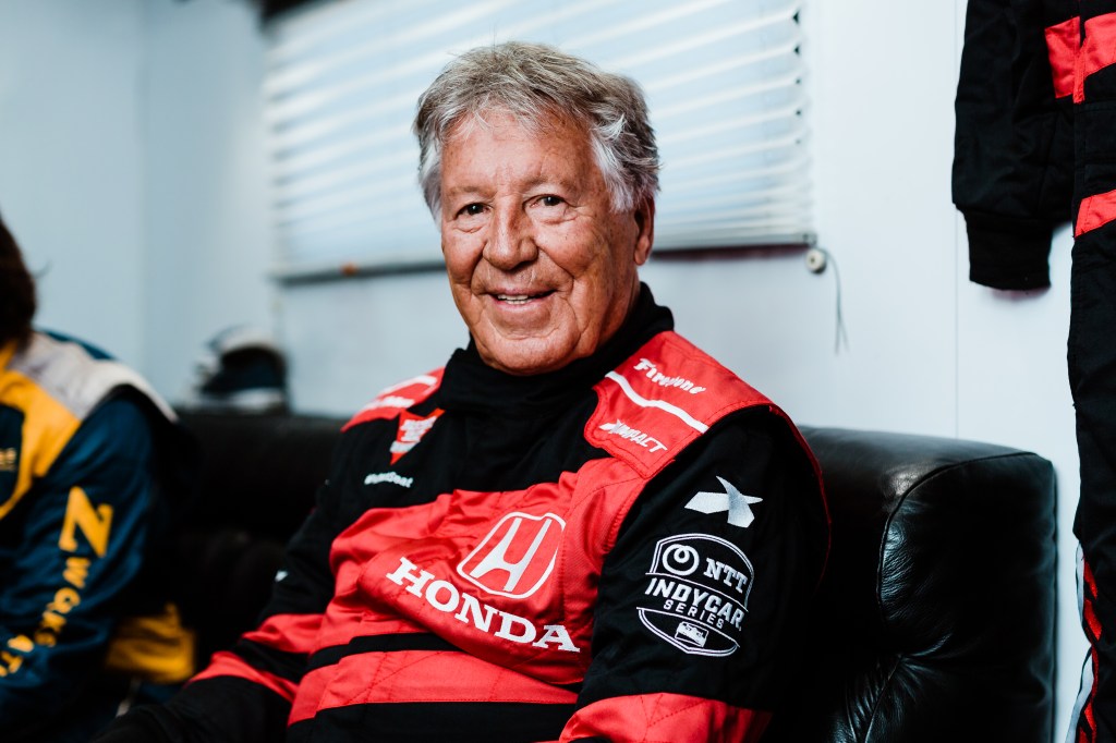 Mario Andretti on a seat in his race suit