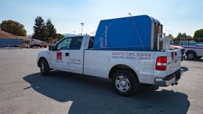 A pickup truck with a sign in the bed turning in a parking lot