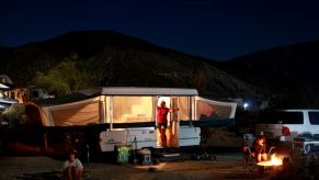 Pop-up camper set up in a campsite complete with a campfire
