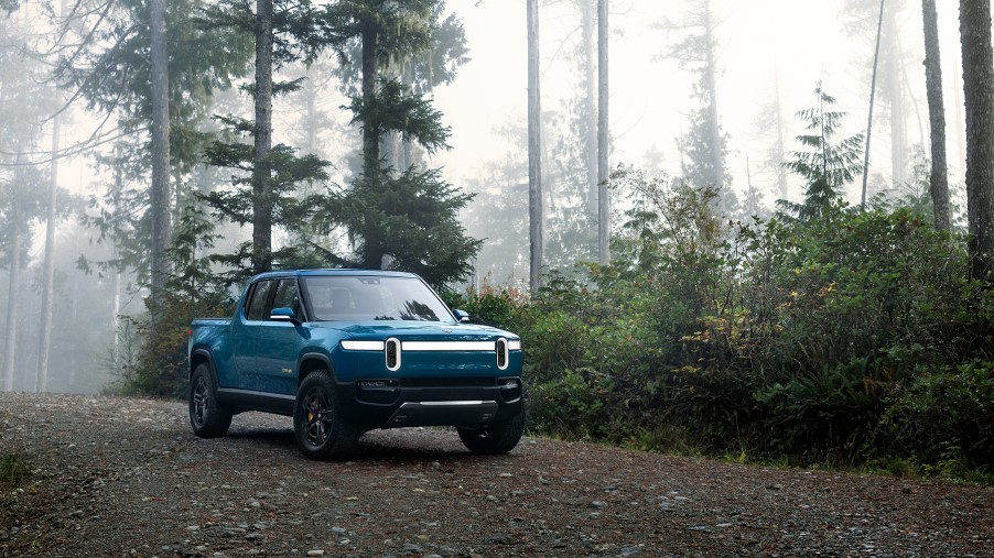 A blue Rivian R1T pickup on a forest road