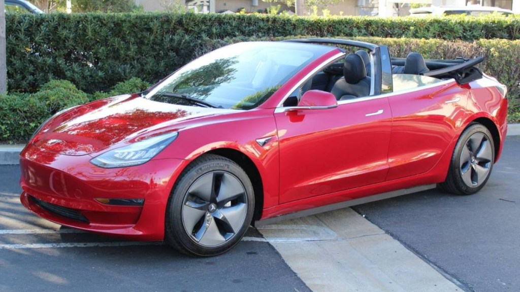 A red Tesla Model 3 has its soft top down