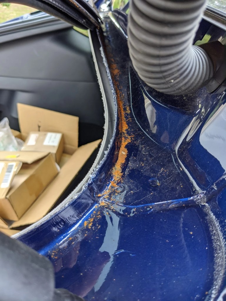 Blue Tesla Model Y's rear hatch, showing rust