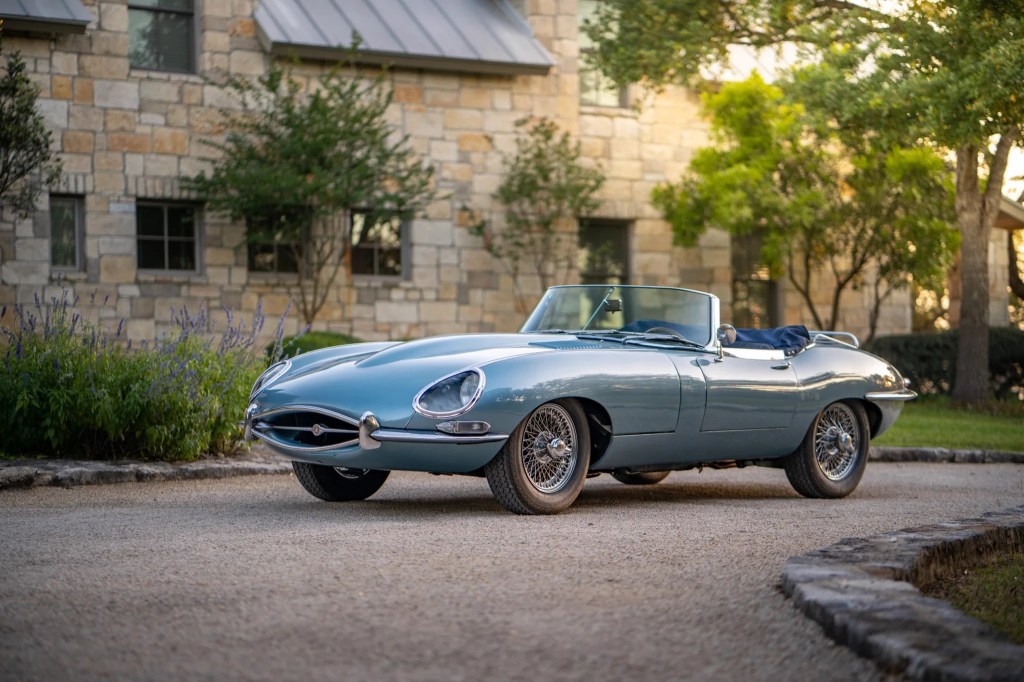 Light-blue 1966 Series 1 Jaguar E-Type convertible in front of a country estate