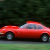 Red 1968 Opel GT, driving down the road, side view