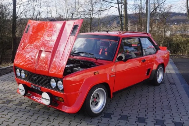 Red 1976 Fiat 131 Abarth Rally with its hood opened