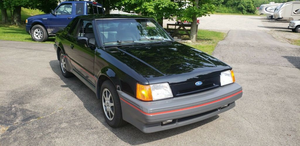 A black second generation Ford EXP is parked in a driveway