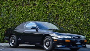 Black 1994 Nissan Silvia coupe in front of a hedge