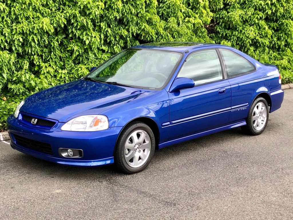 Blue 2000 Honda Civic Si coupe parked in front of a hedge