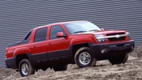 A red 2002 Chevrolet Avalanche sits in front of an industrial building